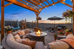 Expansive outdoor deck featuring a wooden pergola, string lighting, built-in fire pit, and durable composite decking - 