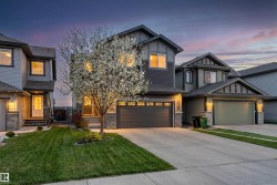 Two-story residence featuring a dark gray facade with stone accents and a prominent flowering tree - 