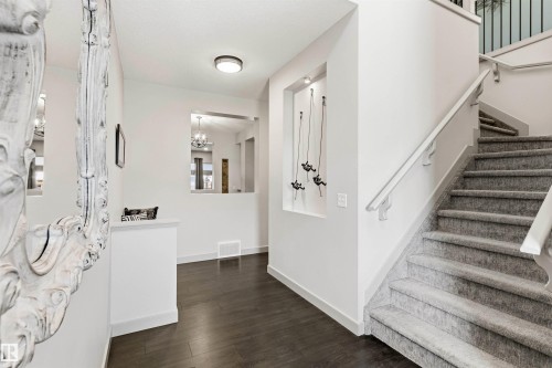 Entryway featuring dark wood-finish flooring and a carpeted staircase with white railings - 7343 Armour Crescent, Edmonton, AB - Indoor Photo Showing Other Room