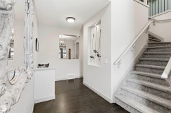 Entryway featuring dark wood-finish flooring and a carpeted staircase with white railings - 