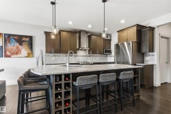 Spacious kitchen featuring an oversized island with a built-in wine rack, stone countertop, and integrated sink - 