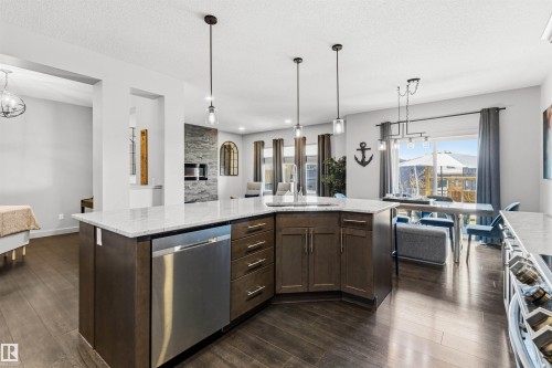 Spacious kitchen island with built-in stainless steel dishwasher, undermount sink, and pendant lighting - 7343 Armour Crescent, Edmonton, AB - Indoor Photo Showing Kitchen With Upgraded Kitchen