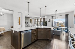 Spacious kitchen island with built-in stainless steel dishwasher, undermount sink, and pendant lighting - 
