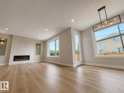 Spacious interior featuring wood-finish flooring, an electric fireplace with a contemporary surround, and recessed lighting - 