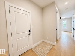 Entryway featuring a white paneled door with black hardware, wood-finish flooring, and light-colored walls - 