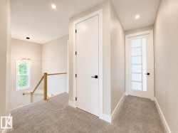 Carpeted hallway featuring a contemporary glass panel door, a solid white door with horizontal detailing, and recessed lighting - 