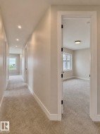 Carpeted hallway featuring recessed lighting and white trim - 