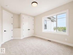 Carpeted room featuring a large window, white trim, and two white doors with black hardware - 