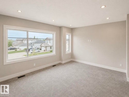 Spacious room featuring gray carpet flooring, neutral paint palette, and recessed ceiling lighting - 16 Middleton Close, Leduc, AB 