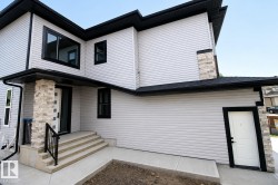 Contemporary exterior featuring light-toned horizontal siding, black-framed windows, a prominent covered entry with stone accents, a multi-tiered concrete staircase, and a secondary entry with black trim - 