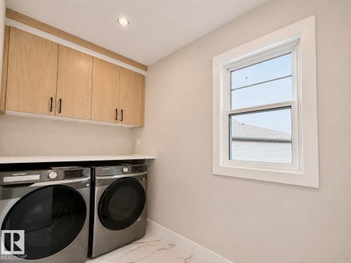 Laundry area featuring light wood-finish cabinetry with black hardware, a white countertop, and a single-pane window with white trim - 16 Middleton Close, Leduc, AB 