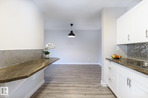 Modern kitchen featuring white cabinetry, a stainless steel sink, and a multi-tone hexagonal tile backsplash - 5816 172 Street, Edmonton, AB - Indoor Photo Showing Kitchen