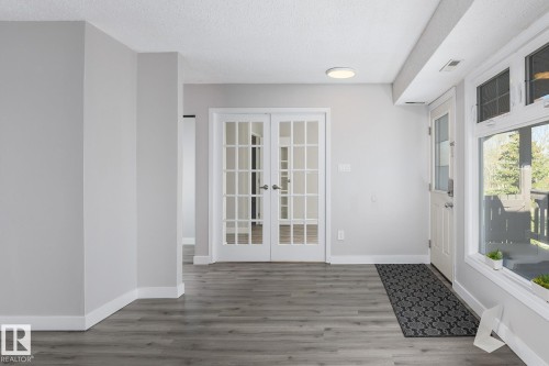 Wood-finish flooring throughout, complemented by light gray walls and white trim - 5816 172 Street, Edmonton, AB - Indoor Photo Showing Other Room