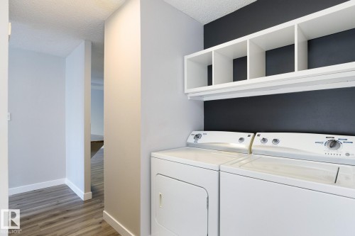 Dedicated laundry area featuring a washer and dryer set, overhead white shelving, and a contrasting accent wall - 5816 172 Street, Edmonton, AB - Indoor Photo Showing Laundry Room