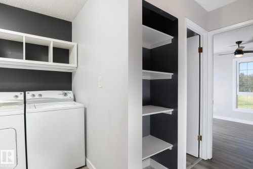 Dedicated laundry area featuring white shelving, a dark accent wall, and built-in white shelving within an adjacent closet - 5816 172 Street, Edmonton, AB - Indoor Photo Showing Laundry Room