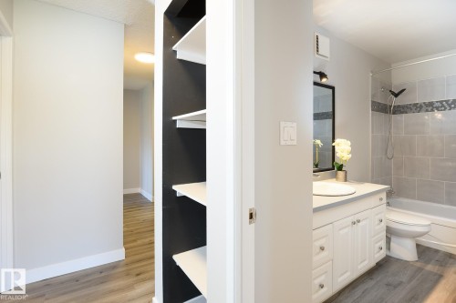 Bathroom featuring a white vanity with paneling and chrome hardware, a white oval sink set into a light-colored countertop, and a shower-over-tub combination with light gray subway tiles and a decorative mosaic accent band - 5816 172 Street, Edmonton, AB - Indoor Photo Showing Bathroom