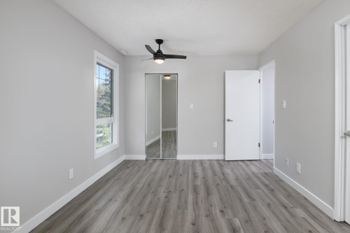 Spacious room featuring wood-finish flooring, light grey walls, and white baseboards - 5816 172 Street, Edmonton, AB - Indoor Photo Showing Other Room