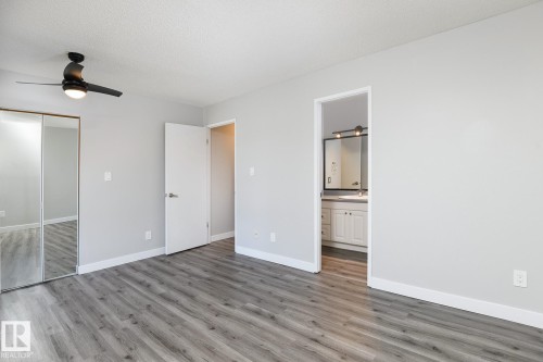 Spacious room featuring wood-finish flooring, light gray walls, and a black ceiling fan with integrated lighting - 5816 172 Street, Edmonton, AB - Indoor Photo Showing Other Room