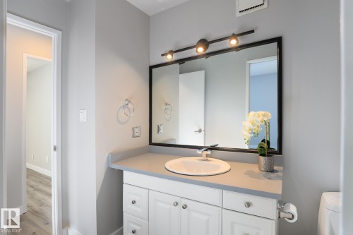 Bathroom vanity featuring a white cabinet base with silver hardware, a light gray countertop, and an undermount sink - 5816 172 Street, Edmonton, AB - Indoor Photo Showing Bathroom