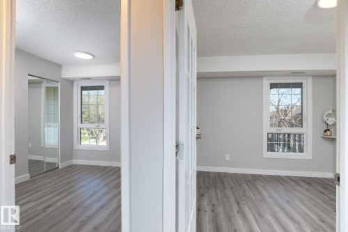 Two distinct rooms featuring wood-finish flooring, white trim, and light gray wall paint - 5816 172 Street, Edmonton, AB - Indoor Photo Showing Other Room