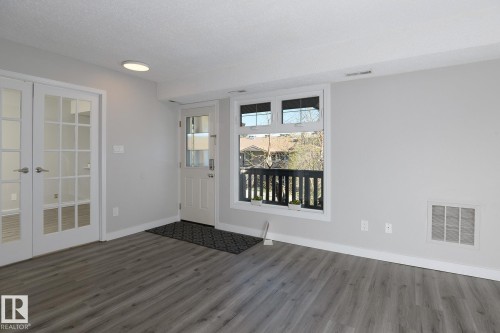 Spacious room featuring wood-finish flooring, light grey wall paint, and white trim - 5816 172 Street, Edmonton, AB - Indoor Photo Showing Other Room