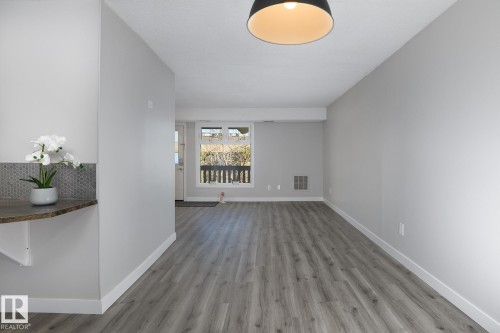 Spacious room featuring wood-finish flooring, light grey walls, and white trim - 5816 172 Street, Edmonton, AB - Indoor Photo Showing Other Room