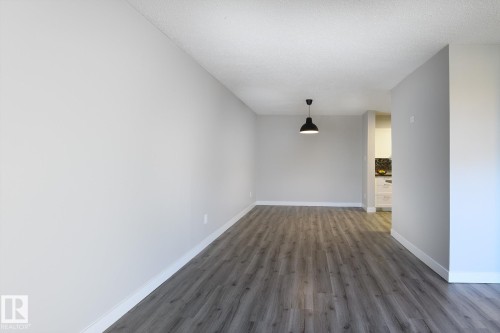 Spacious interior room featuring wood-finish flooring, light gray walls, a textured white ceiling, and white baseboards - 5816 172 Street, Edmonton, AB - Indoor Photo Showing Other Room
