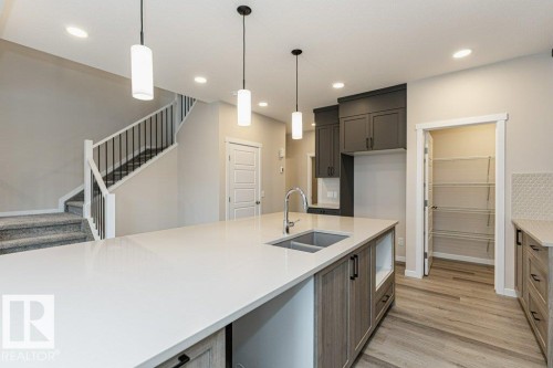 Spacious kitchen island with a double basin stainless steel sink, extending to light wood-finish cabinetry - 2616 158 Street, Edmonton, AB - Indoor Photo Showing Kitchen With Double Sink With Upgraded Kitchen