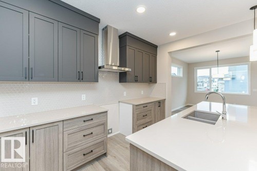 Modern kitchen featuring a large island with an undermount sink and chrome faucet - 2616 158 Street, Edmonton, AB - Indoor Photo Showing Kitchen With Double Sink