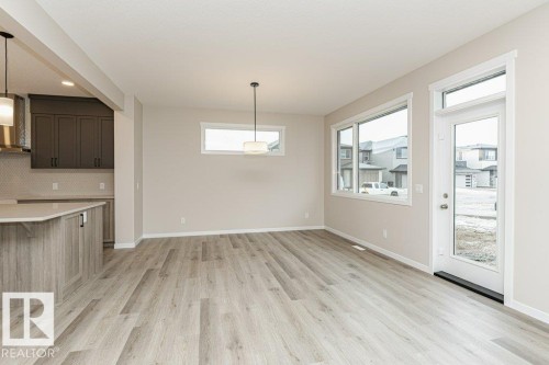 Open-concept living area with light wood-finish flooring, ample natural light from multiple windows, and a glass-paneled door - 2616 158 Street, Edmonton, AB - Indoor