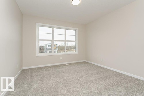 Room featuring light gray carpet, neutral painted walls, white trim, a large multi-pane window, and a flush-mount ceiling light - 2616 158 Street, Edmonton, AB - Indoor Photo Showing Other Room