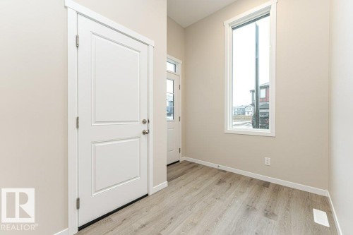 Entryway featuring durable wood-finish flooring, neutral wall tones, white trim, and a tall window - 2616 158 Street, Edmonton, AB - Indoor Photo Showing Other Room