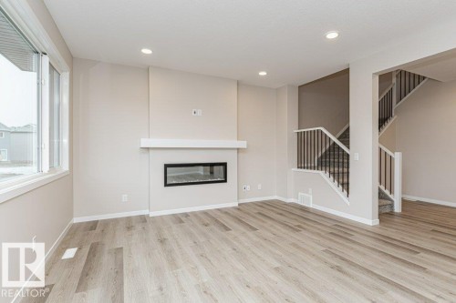 Living area featuring wood-finish flooring, a contemporary fireplace with a white mantel, and recessed lighting - 2616 158 Street, Edmonton, AB - Indoor Photo Showing Other Room With Fireplace