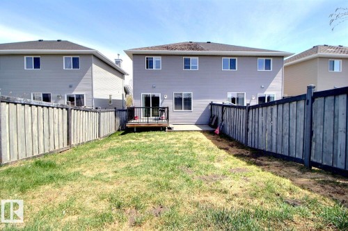 Enclosed backyard featuring a wooden privacy fence, a wooden deck with black railings, and a concrete patio - 170 Keystone Crescent, Leduc, AB - Outdoor With Exterior
