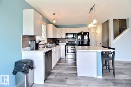 Modern kitchen featuring white cabinetry, light-toned countertops, and a tiled backsplash - 170 Keystone Crescent, Leduc, AB - Indoor Photo Showing Kitchen With Double Sink