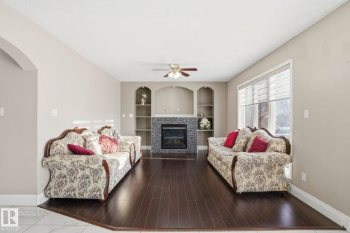 This inviting living space features dark hardwood flooring and a fireplace with a tiled surround - 4831 154 Avenue, Edmonton, AB - Indoor Photo Showing Living Room With Fireplace