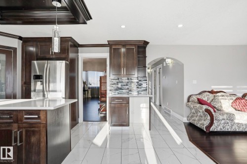 The kitchen features dark wood cabinetry, a stainless steel refrigerator, and white countertops - 4831 154 Avenue, Edmonton, AB - Indoor Photo Showing Kitchen
