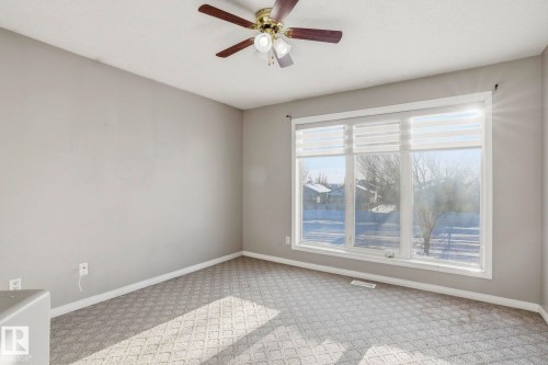 This room features neutral-toned walls, patterned carpeting, and a ceiling fan with integrated lighting - 4831 154 Avenue, Edmonton, AB - Indoor Photo Showing Other Room
