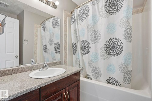 Bathroom featuring a vanity with a white oval sink, a light-colored countertop, and a mirror - 4831 154 Avenue, Edmonton, AB - Indoor Photo Showing Bathroom