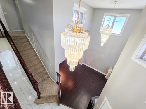 Grand foyer featuring two tiered chandeliers, a carpeted staircase with dark wood railings, and dark wood flooring - 4831 154 Avenue, Edmonton, AB - Indoor Photo Showing Other Room