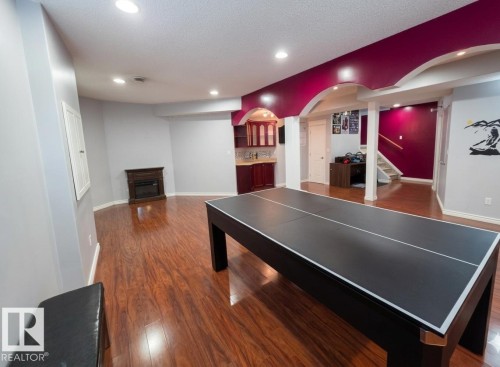 Spacious room with a brown wood floor, a corner fireplace, and recessed lighting - 4831 154 Avenue, Edmonton, AB - Indoor Photo Showing Other Room
