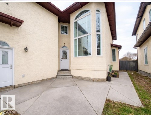 The property features a stucco exterior, a prominent arched window, and a white front door with an arched transom - 4831 154 Avenue, Edmonton, AB - Outdoor