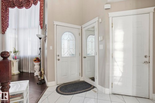 Inviting entryway featuring white tile flooring, a decorative front door with an arched window, and warm neutral wall colors - 4831 154 Avenue, Edmonton, AB - Indoor Photo Showing Other Room