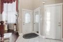 Inviting entryway featuring white tile flooring, a decorative front door with an arched window, and warm neutral wall colors - 4831 154 Avenue, Edmonton, AB  - Indoor Photo Showing Other Room 