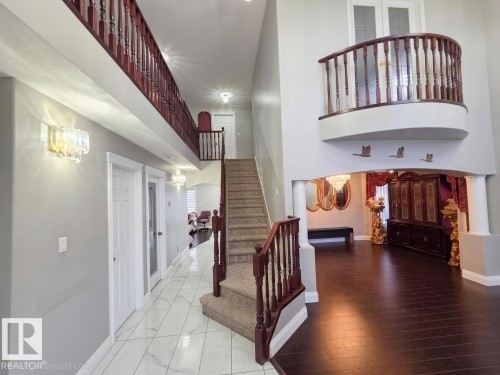 The grand foyer features a high ceiling, a carpeted staircase with a dark wood banister, and a curved landing overlooking the entrance - 4831 154 Avenue, Edmonton, AB - Indoor Photo Showing Other Room
