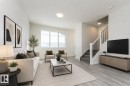 Open-concept living area featuring light wood-finish flooring, a contemporary staircase with black iron spindles, large multi-pane windows, and recessed lighting - 3896 Wren Crescent, Edmonton, AB  - Indoor Photo Showing Living Room 