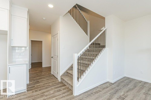 Contemporary staircase featuring carpeted treads and dark metal balusters - 6271 180 Avenue, Edmonton, AB - Indoor Photo Showing Other Room