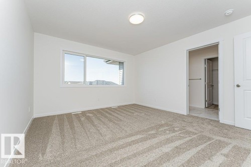 Spacious room with plush carpet flooring, a large window, and an overhead light fixture - 6271 180 Avenue, Edmonton, AB - Indoor Photo Showing Other Room