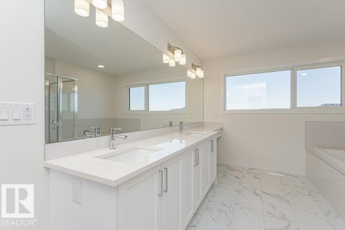 Modern bathroom featuring a double vanity with white cabinetry, polished chrome faucets, and a continuous mirror - 6271 180 Avenue, Edmonton, AB - Indoor Photo Showing Bathroom