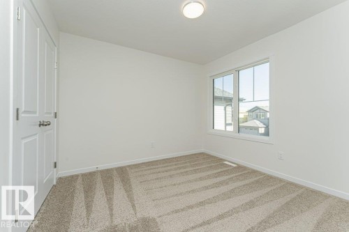 Bright room featuring a large window, neutral carpeting, white trim, and a flush mount ceiling light fixture - 6271 180 Avenue, Edmonton, AB - Indoor Photo Showing Other Room